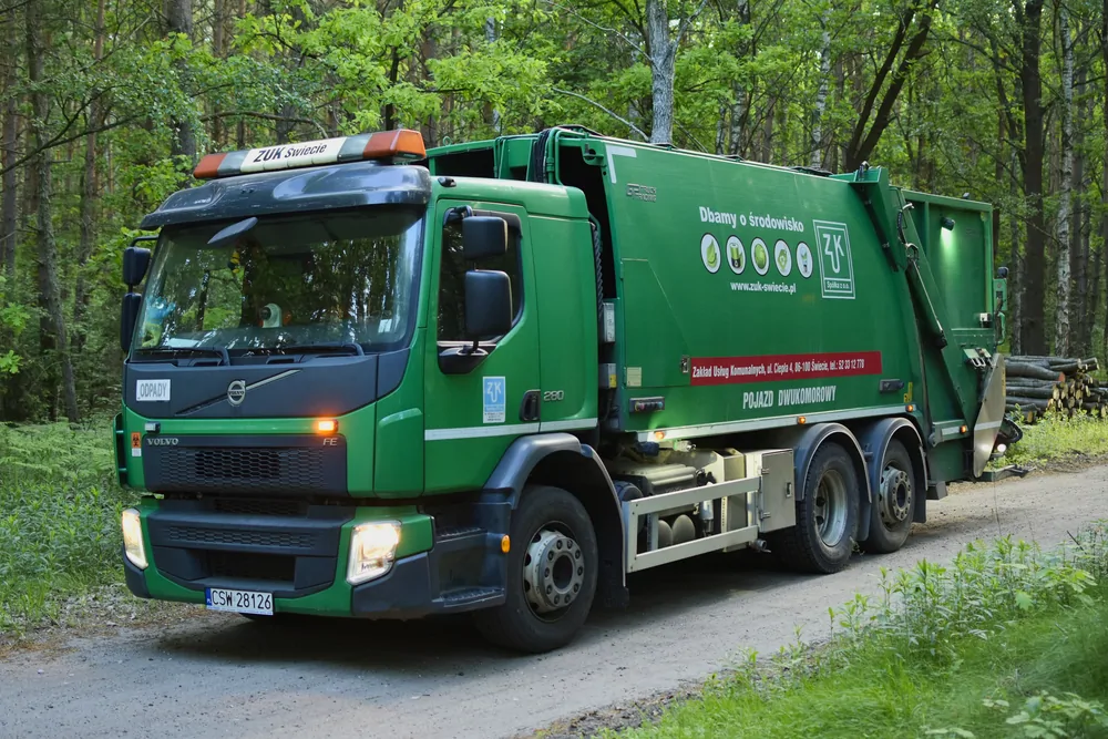 Zielona śmieciarka Volvo w lesie, ujęcie trzy czwarte